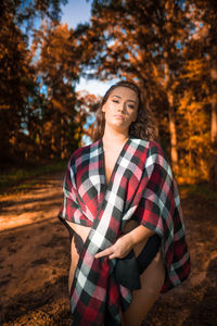 Beautiful young woman standing against trees during autumn