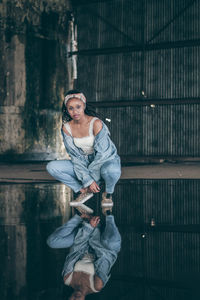 Portrait of young woman standing against wall