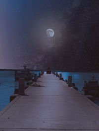 Pier over sea against sky at night