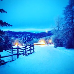 Snow covered street against blue sky at dusk