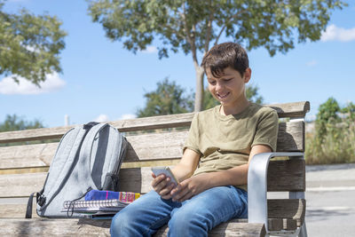 Man using mobile phone while sitting on bench