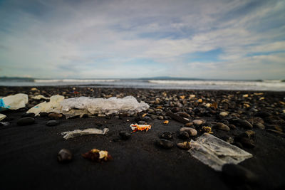 Surface level of pebbles on beach against sky