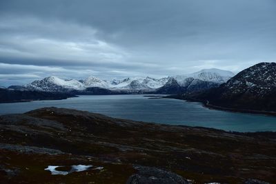 Scenic view of lake by snowcapped mountains against sky