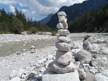 Stone stack on rocks by sea against sky