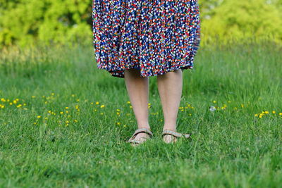 Woman with flower skirt close up bare legs in gras spring summer