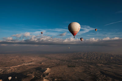 Hot air balloons flying over landscape against sky