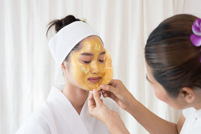 Massage therapist removing facial mask from young woman face