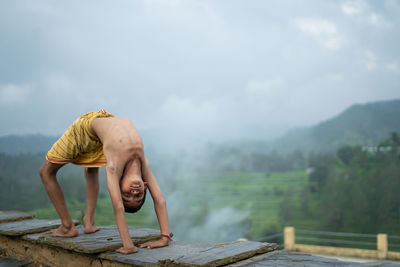 Full length of man climbing on wood against sky