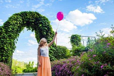 Woman holding umbrella against plants