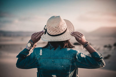 Rear view of woman wearing hat against sea against sky