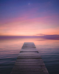 Pier over sea against sky at sunset