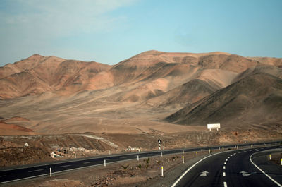 Highway by mountains against sky