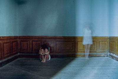 Rear view of woman standing against wall at home