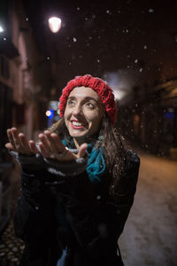 Young woman standing against illuminated wall during winter at night