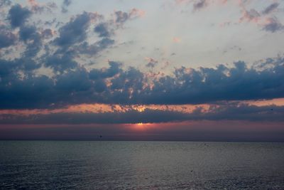 Scenic view of sea against dramatic sky during sunset