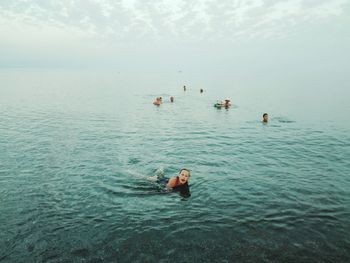 High angle view of people swimming in sea against sky