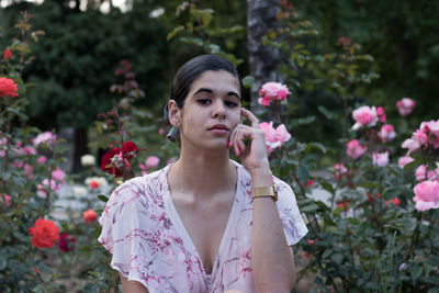 Young woman standing by flowers in park