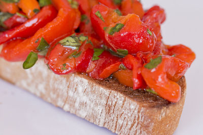 Close up of a slice of bruschetta with red sweet filleted peppers.