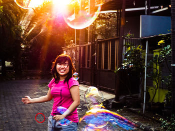 Young woman holding hands while standing on sidewalk