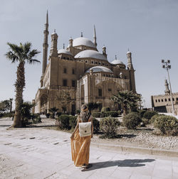 Rear view of woman standing against castle during sunny day