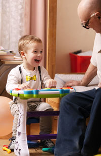 Grandson and grandfather playing with toy at home