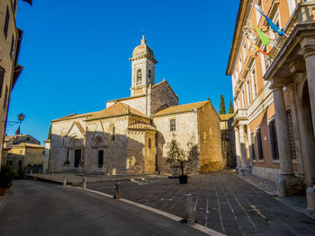 Street amidst buildings against clear blue sky