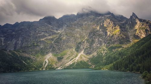 Scenic view of lake by mountains against sky