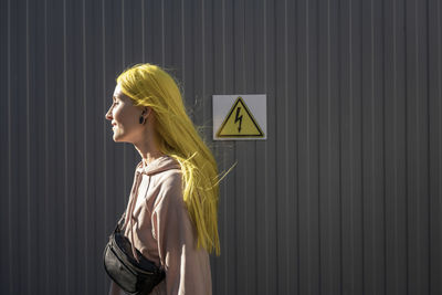 Side view of a young woman standing against wall