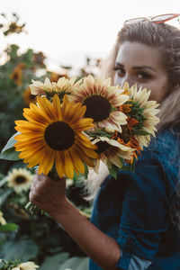 Young woman with sunflowers on yellow flowering plant