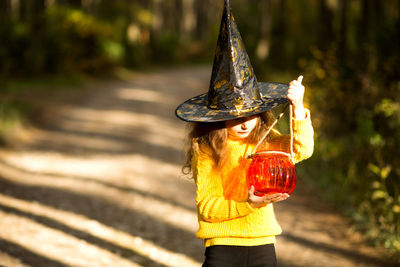 Woman holding hat standing outdoors