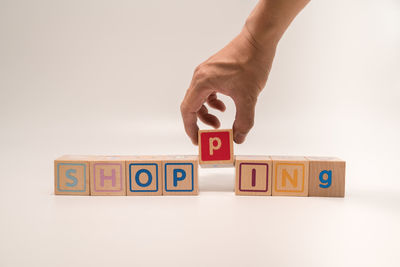 Close-up of hand holding toy blocks against white background