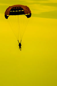 Person paragliding against yellow sky