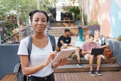 Portrait of young woman using digital tablet while sitting on table