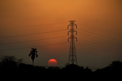 Low angle view of silhouette electricity pylon against sky during sunset