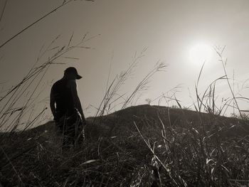 Silhouette man on field against sky during sunset