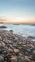 Pebbled shore on beach at sunset