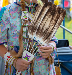 Midsection of woman holding hand fan