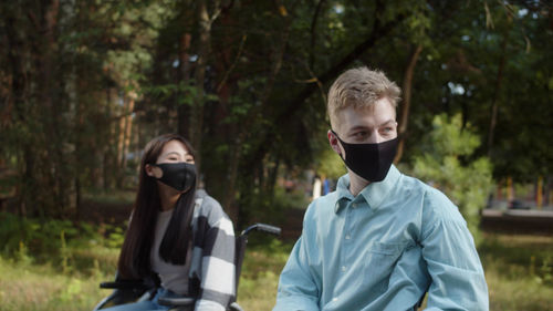 Couple wearing mask looking away at park