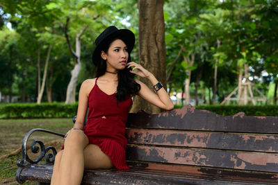Young woman looking away while sitting on bench