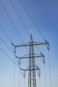 Low angle view of electricity pylon against clear sky