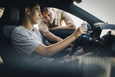 Father teaching son to drive car