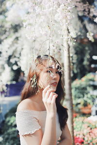 Young woman standing by plants in park