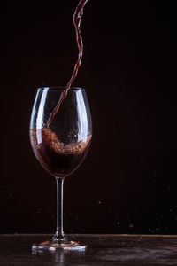 Close-up of wineglass on table against black background