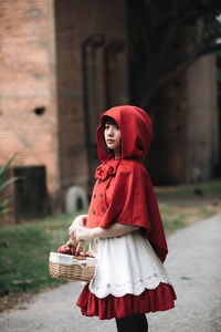 Midsection of woman standing by red wicker basket