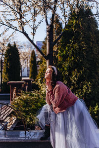 Side view of woman standing on retaining wall at park