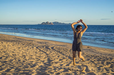 Full length of woman standing on beach against sky