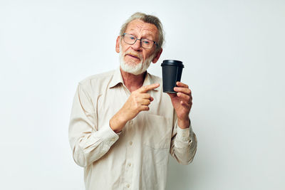 Senior man holding coffee cup in studio