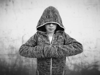 Girl wearing hooded jacket standing against wall