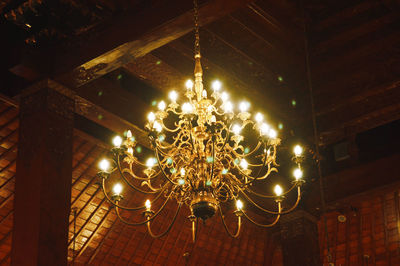 Low angle view of illuminated chandelier hanging on ceiling in building