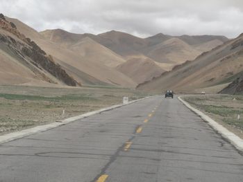 Road by mountain against sky